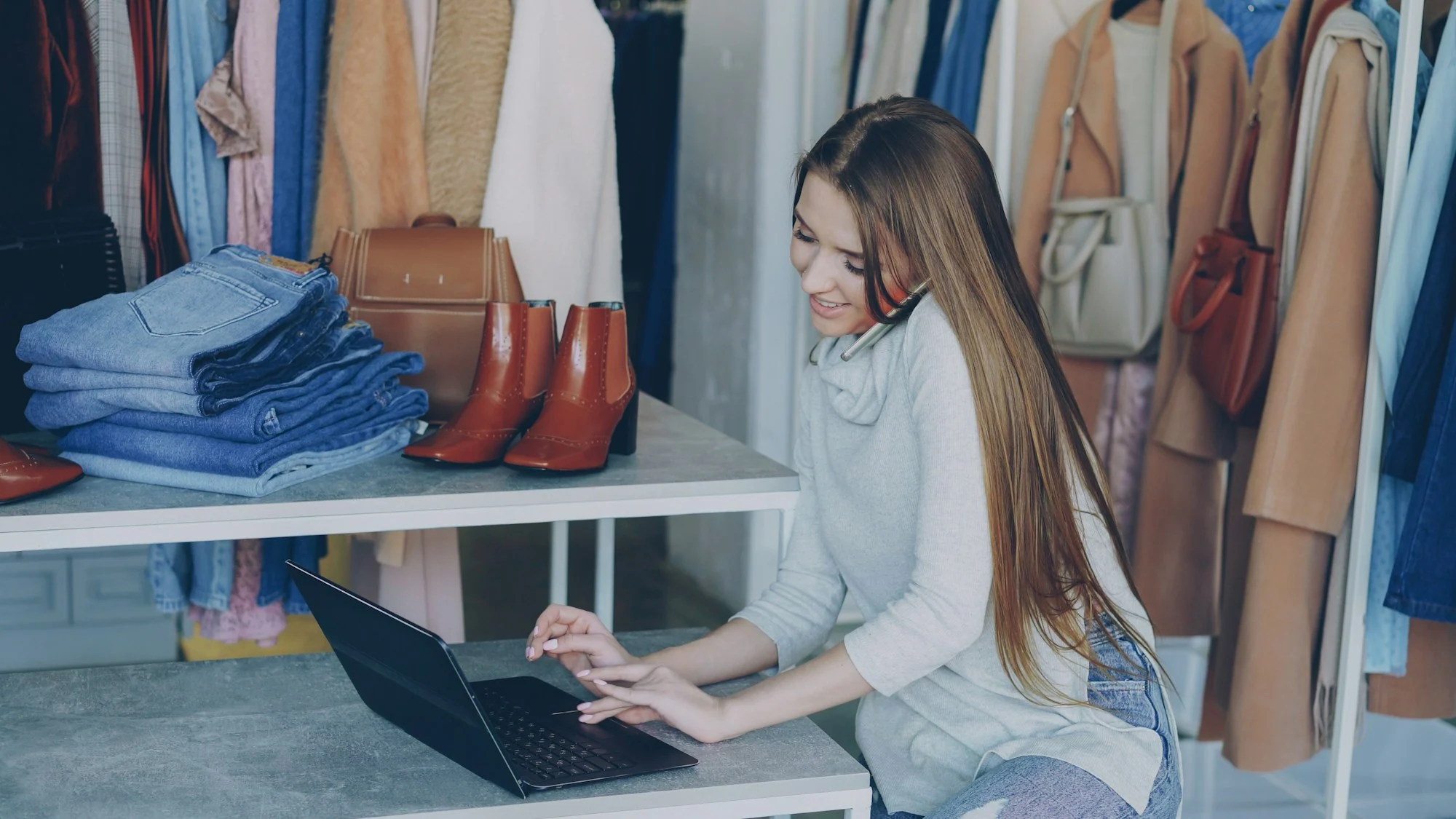 A retailer working on a laptop in a clothing store